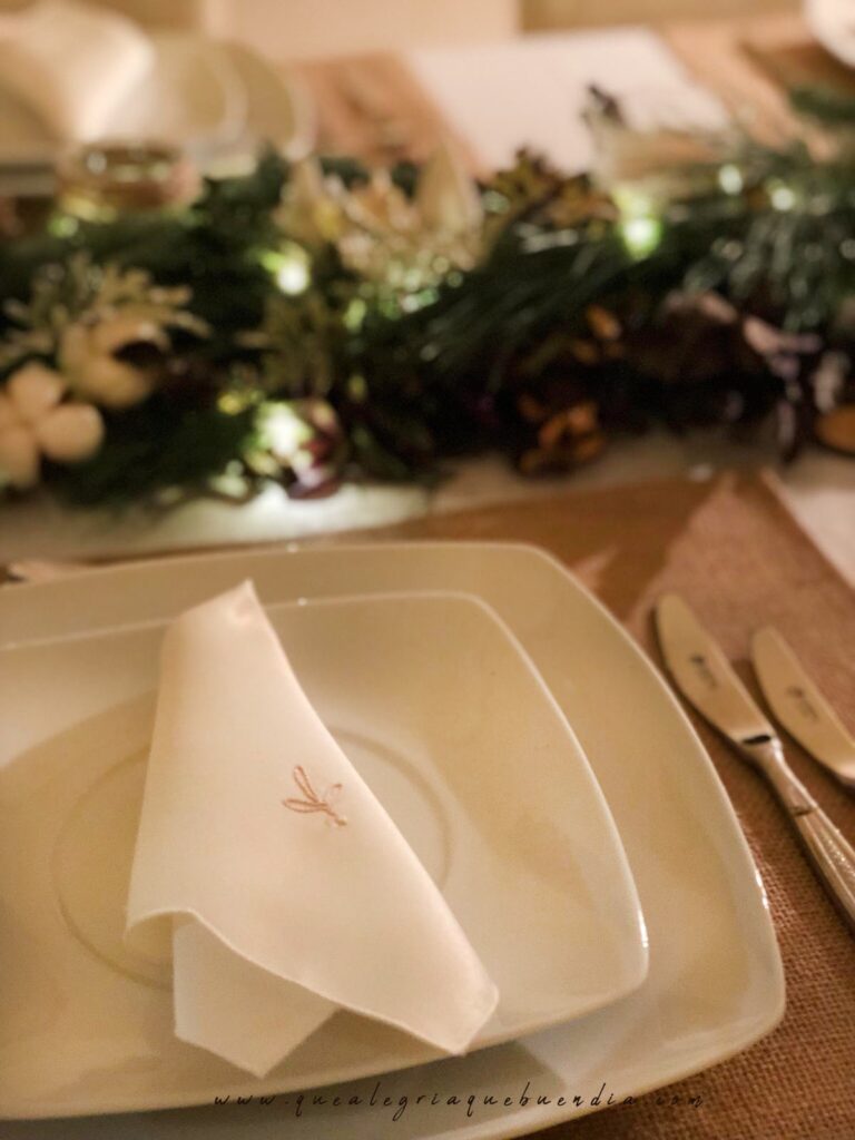 Decoracion Mesa Navidad compuesta por diferentes ramas verdes, velas, piñas, y más elementos decorativos.