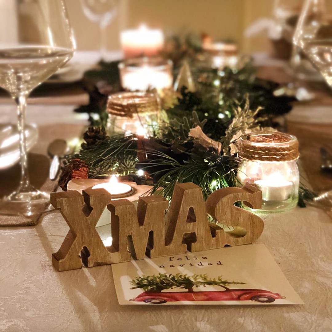 Decoracion Mesa Navidad compuesta por diferentes ramas verdes, velas, piñas, y más elementos decorativos.