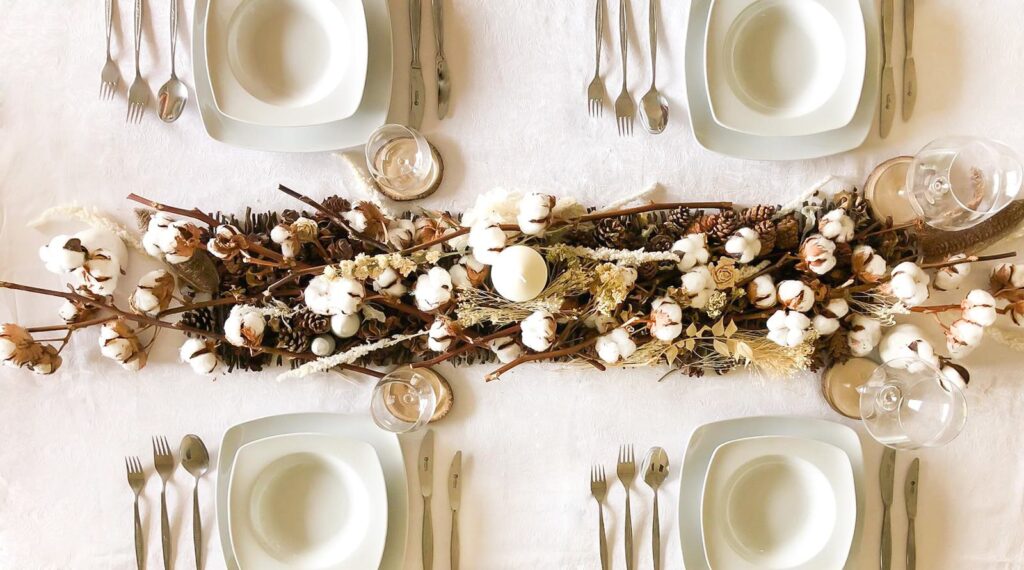 Vista desde arriba de la decoración mesa navidad en tonos cremas blancos marrones y tostados hechas con flores y ramajes