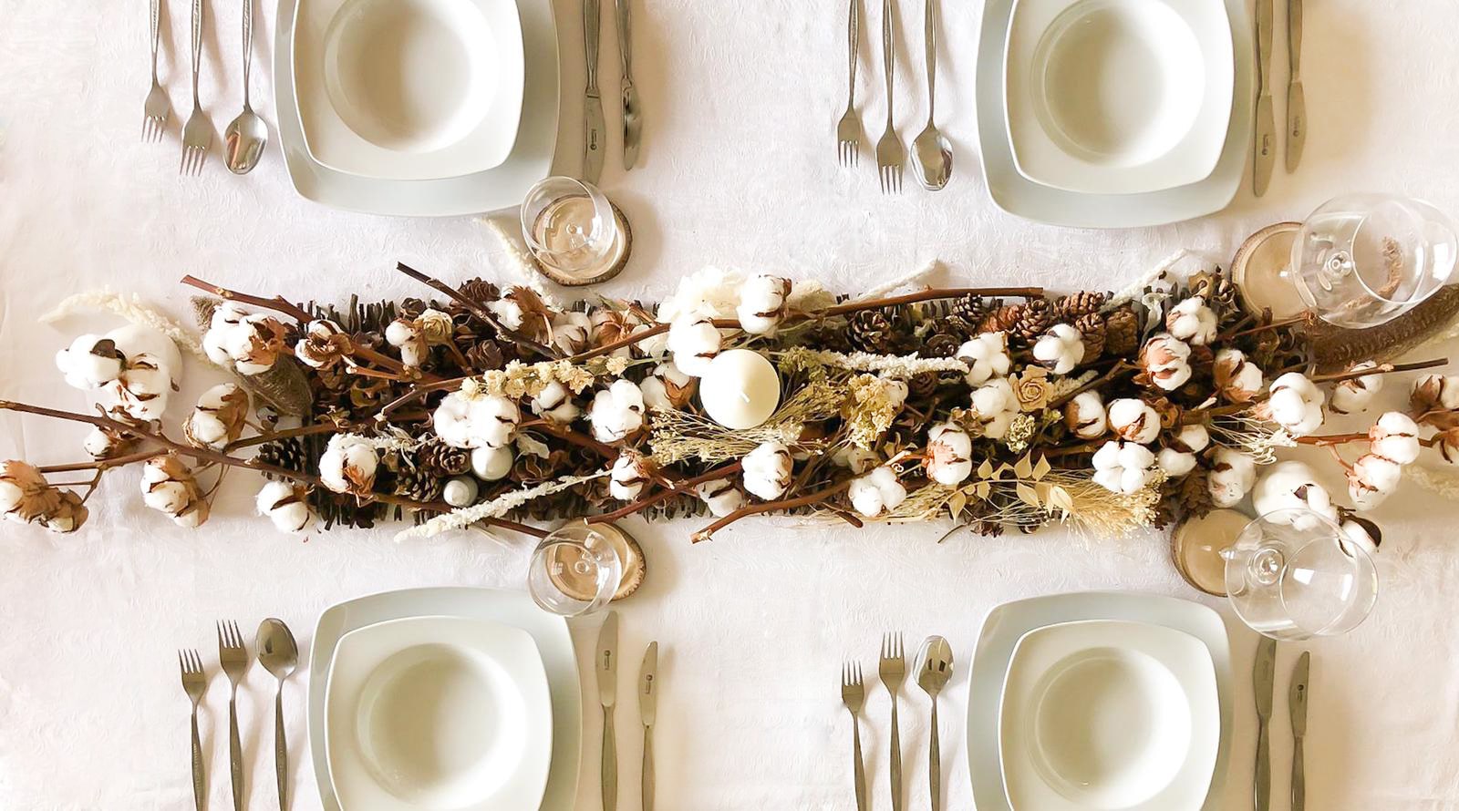 Vista desde arriba de la decoración mesa navidad en tonos cremas blancos marrones y tostados hechas con flores y ramajes