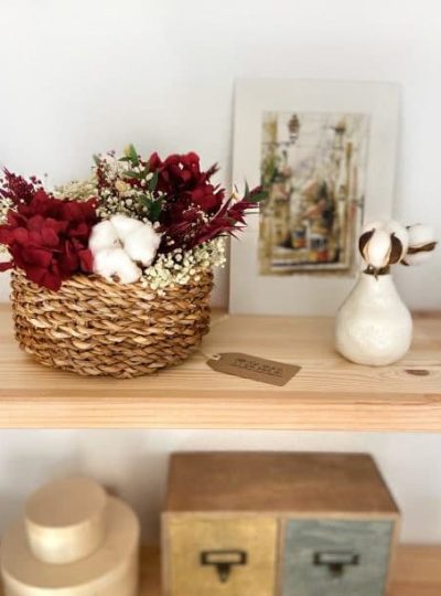 Cesto de flores preservadas en tonos burdeos en cesta de mimbre