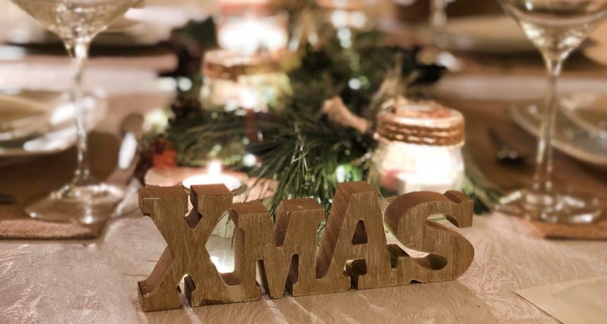 Decoracion Mesa Navidad compuesta por diferentes ramas verdes, velas, piñas, y más elementos decorativos.